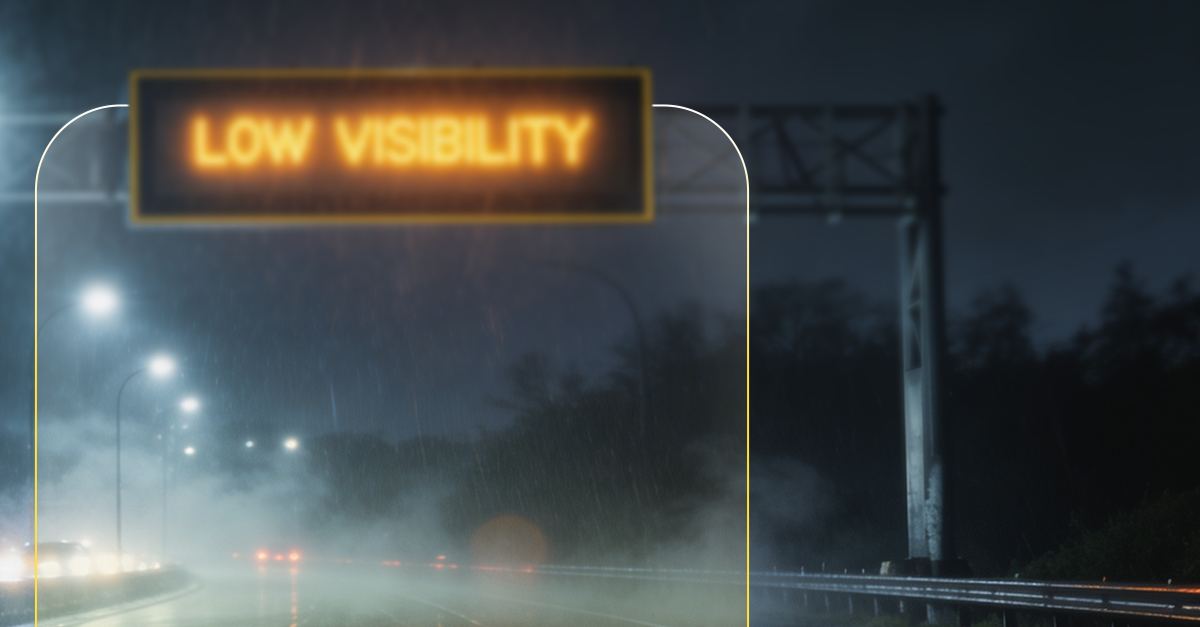 Highway sign reading Low Visibility on a foggy night